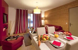 Une chambre d’hôtel moderne dotée d’un coin repas, d’un canapé et d’un mur décoratif en bois.