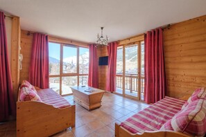 Two comfortable beds, a desk, and a chair are featured in this room, offering a view of the surrounding landscape.