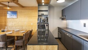 Una cocina moderna con una isla central, electrodomésticos integrados y una zona de comedor de madera.