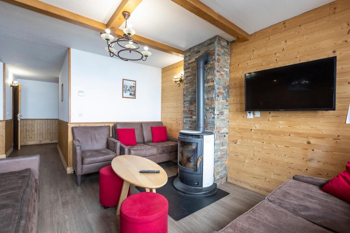 A cozy living room with a fireplace, wooden walls, a sofa, and a television.