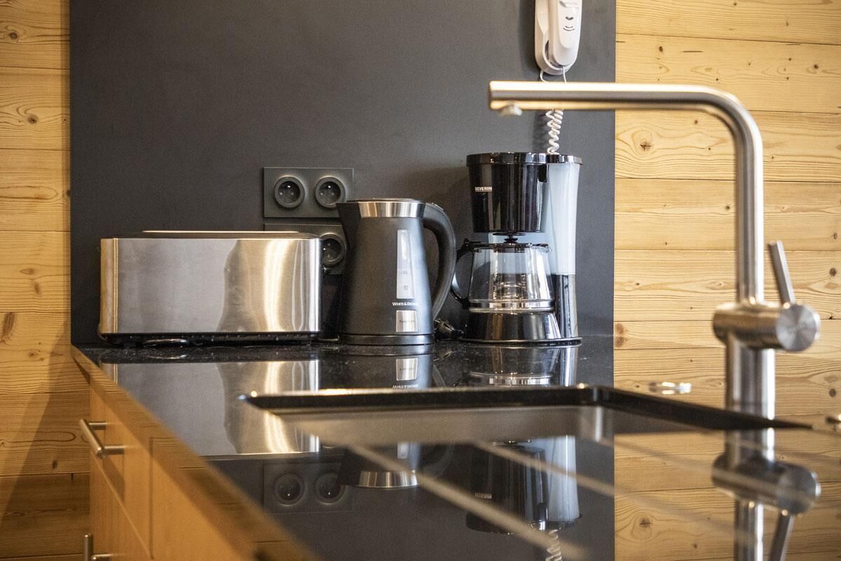 Eine Küche mit einem Edelstahltoaster, einer Kaffeemaschine und einem modernen Wasserhahn.