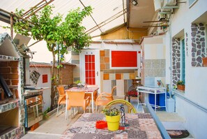 A compact outdoor kitchen area with a dining table, chairs, and a small plant. - B&B Cappotto Civico 48 (Pompei)