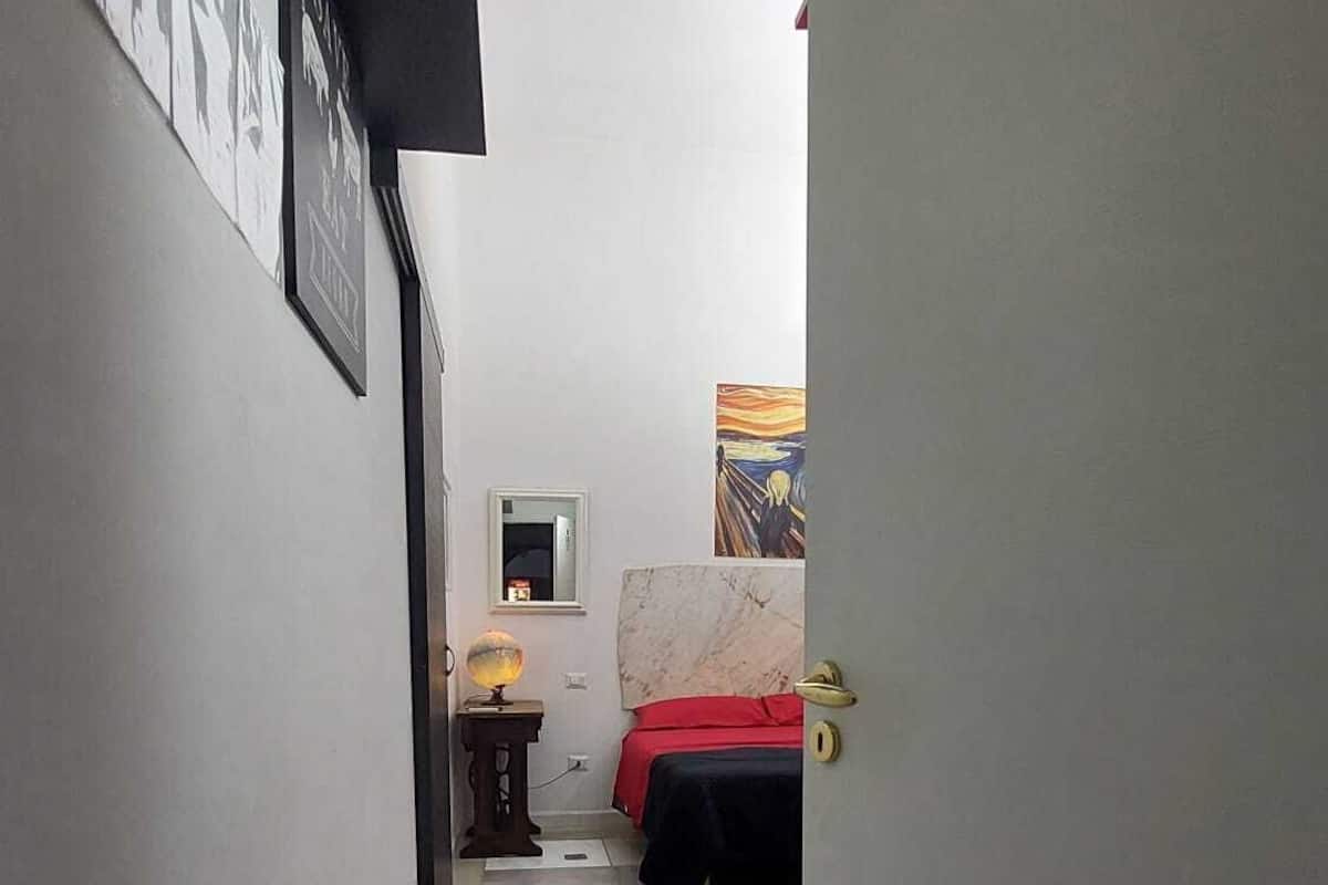 A narrow hallway with a bed, a nightstand, and a lamp.