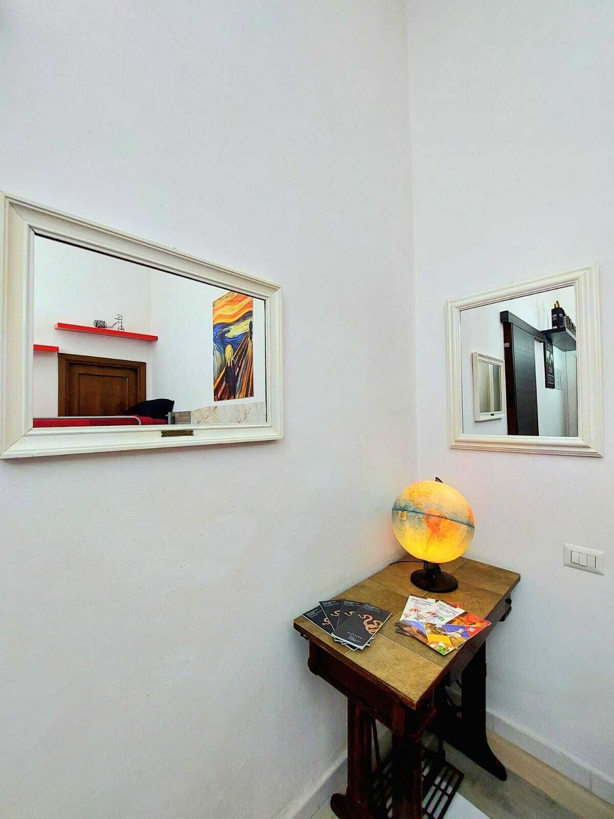 A room with a wooden desk, a globe, and two framed mirrors on the wall.