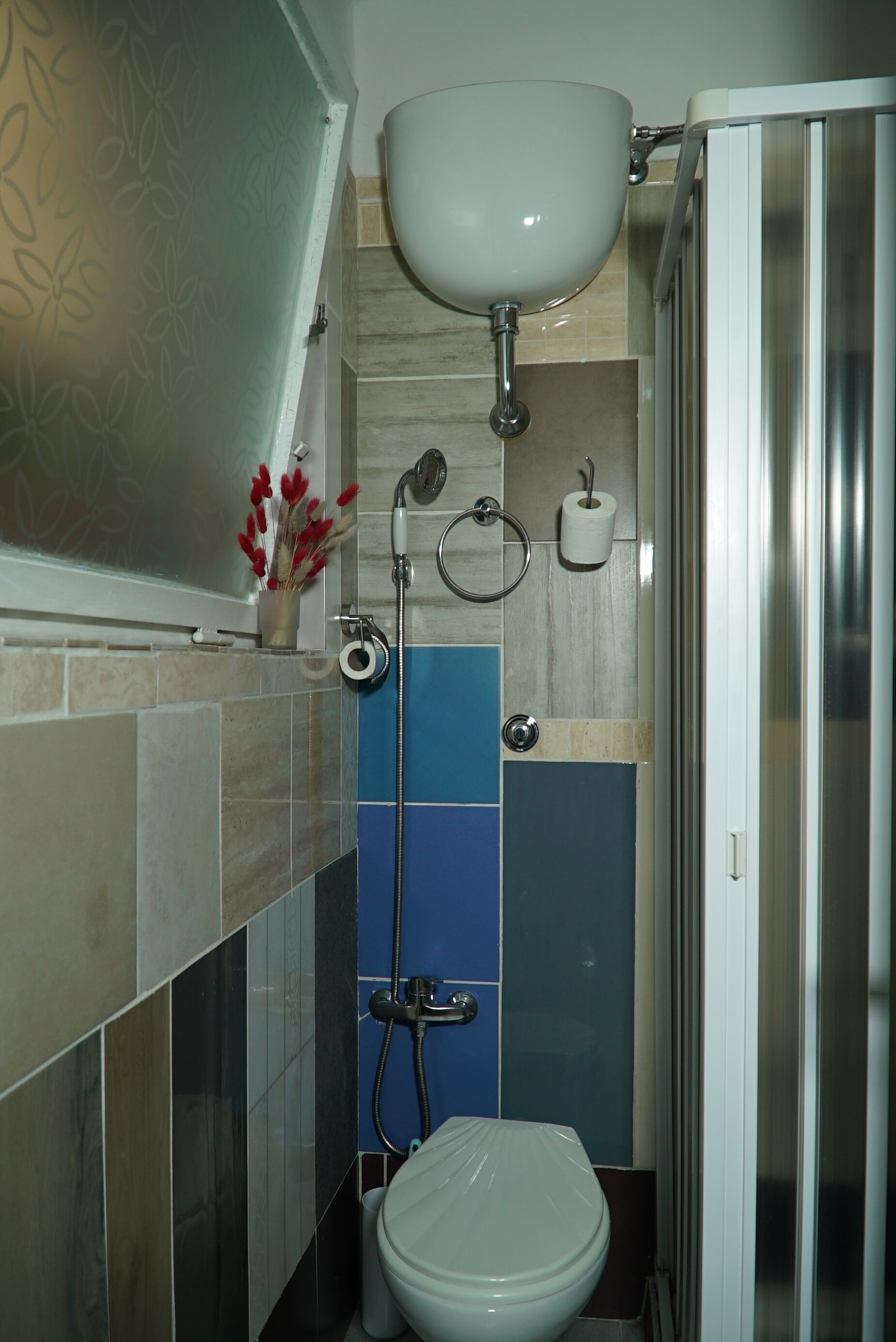 A bathroom with a toilet, sink, shower, and a glass shower door.