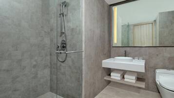 Un baño moderno con ducha envuelta en vidrio, un lavabo blanco y un espejo grande.