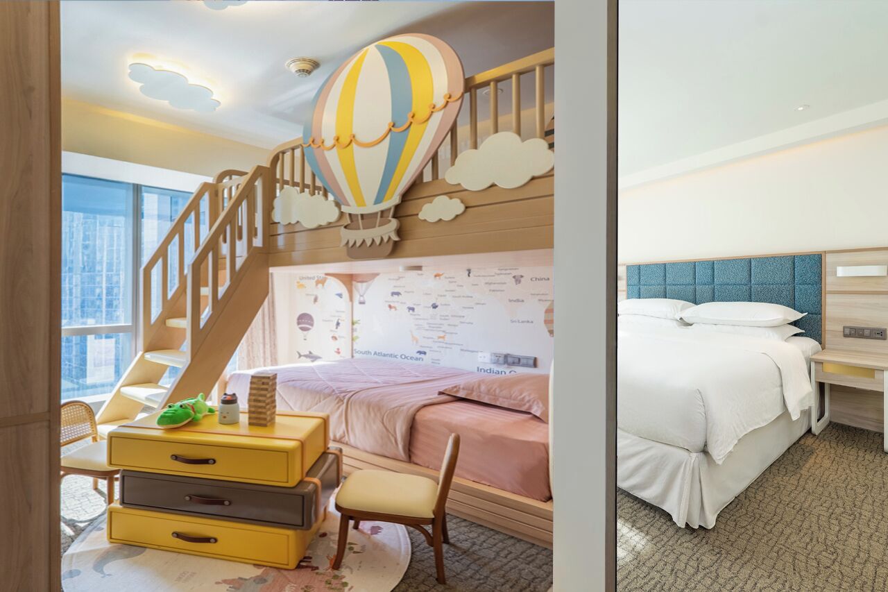 Une chambre d’enfant avec un lit superposé, une décoration représentant une montgolfière et une carte du monde accrochée au mur.