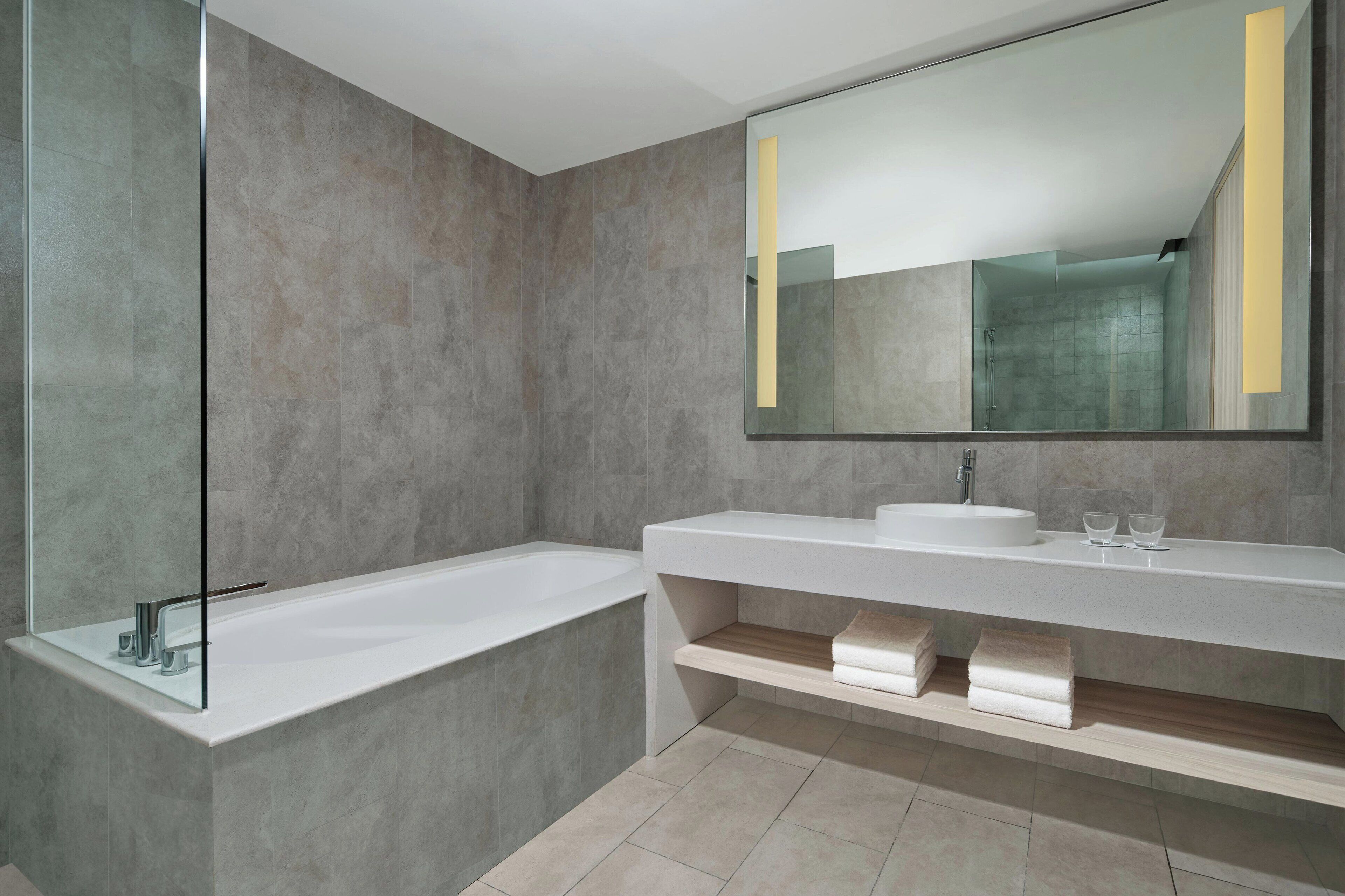 A modern bathroom with a large bathtub, a vanity with a mirror, and a shower area.