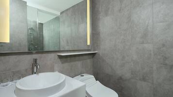 Une salle de bain moderne avec un lavabo blanc, des toilettes et un miroir au-dessus du lavabo.