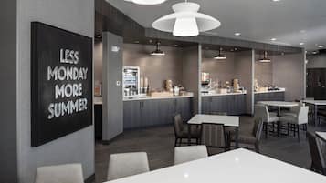 Un restaurante moderno con una zona de bar, varias mesas para comer y un cartel llamativo en la pared.