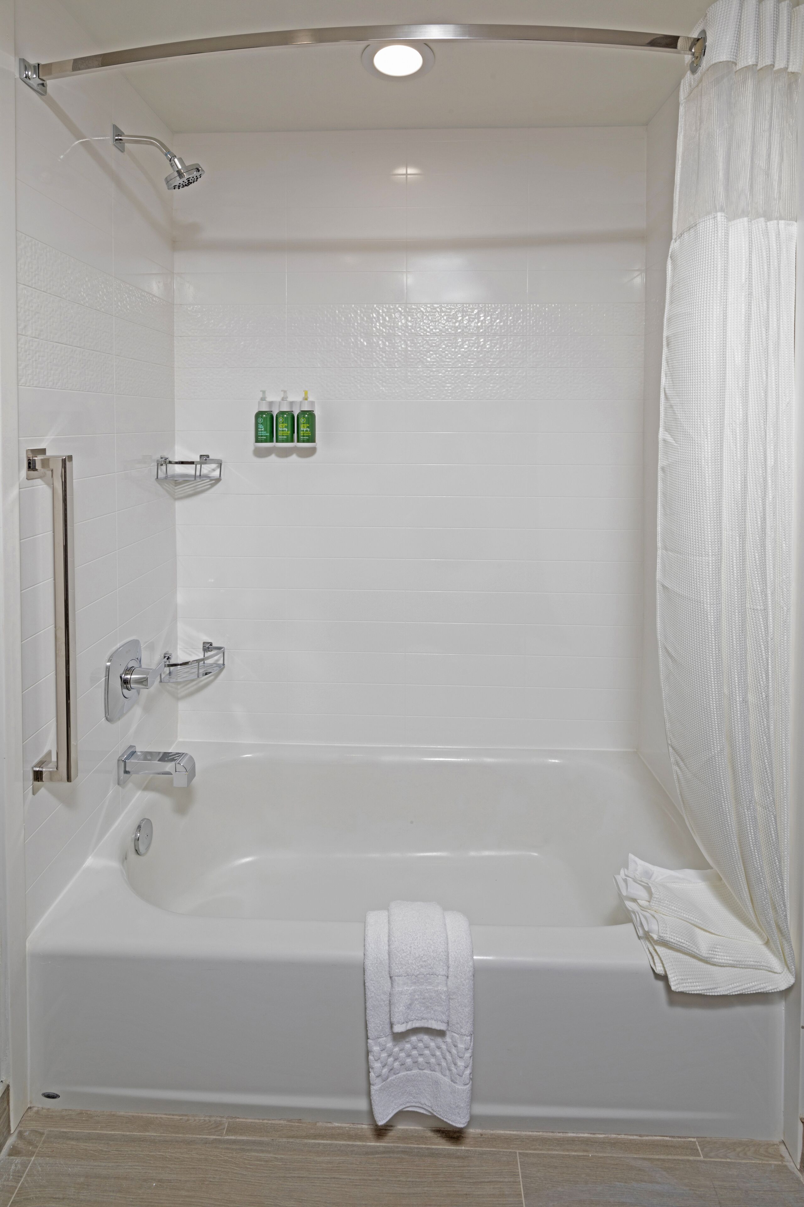 Un baño blanco con bañera, ducha y barandilla.