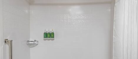 Un baño blanco con bañera, ducha y barandilla.