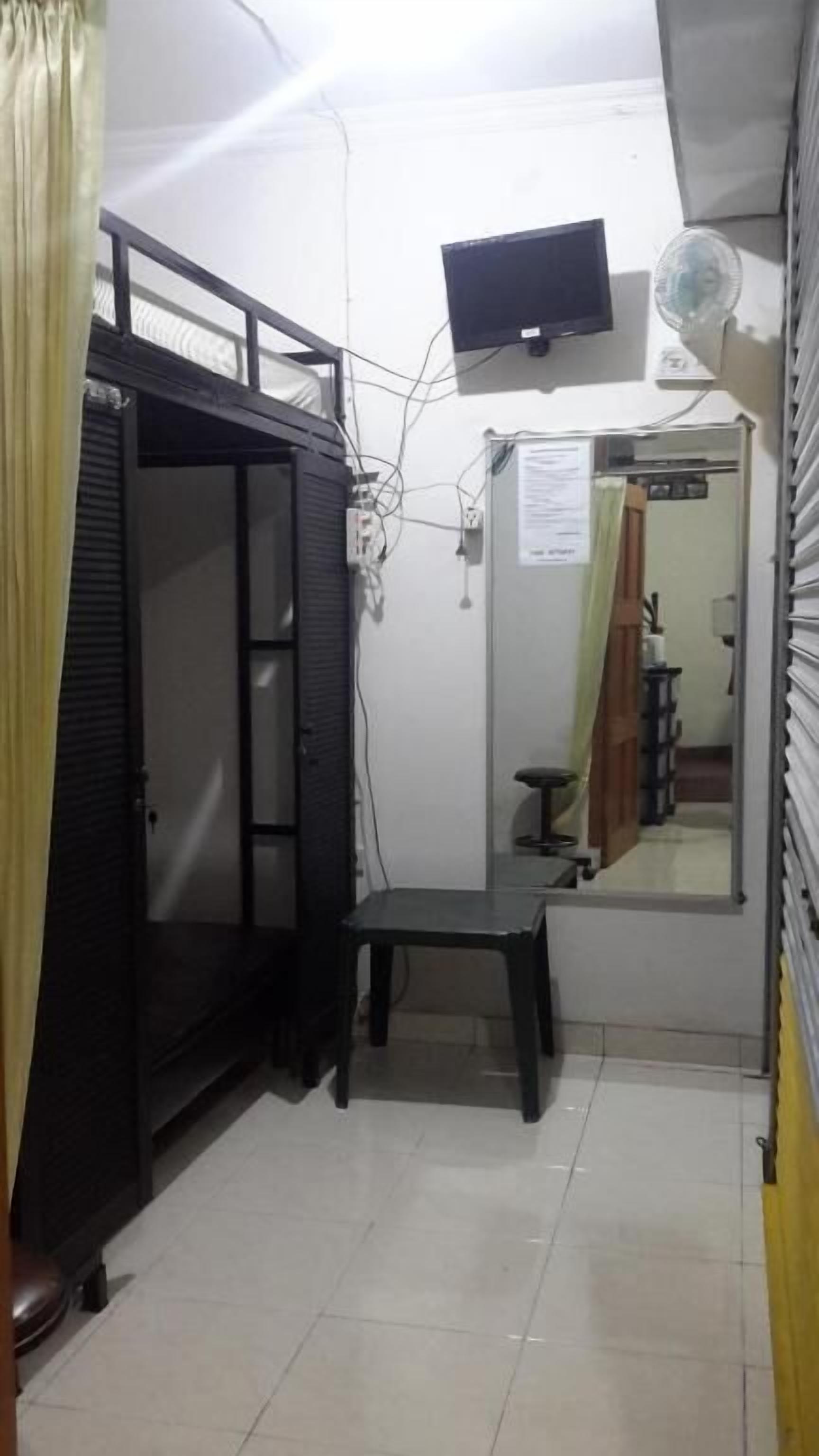 Habitación pequeña con una litera, una mesita, un espejo y un televisor fijado a la pared.