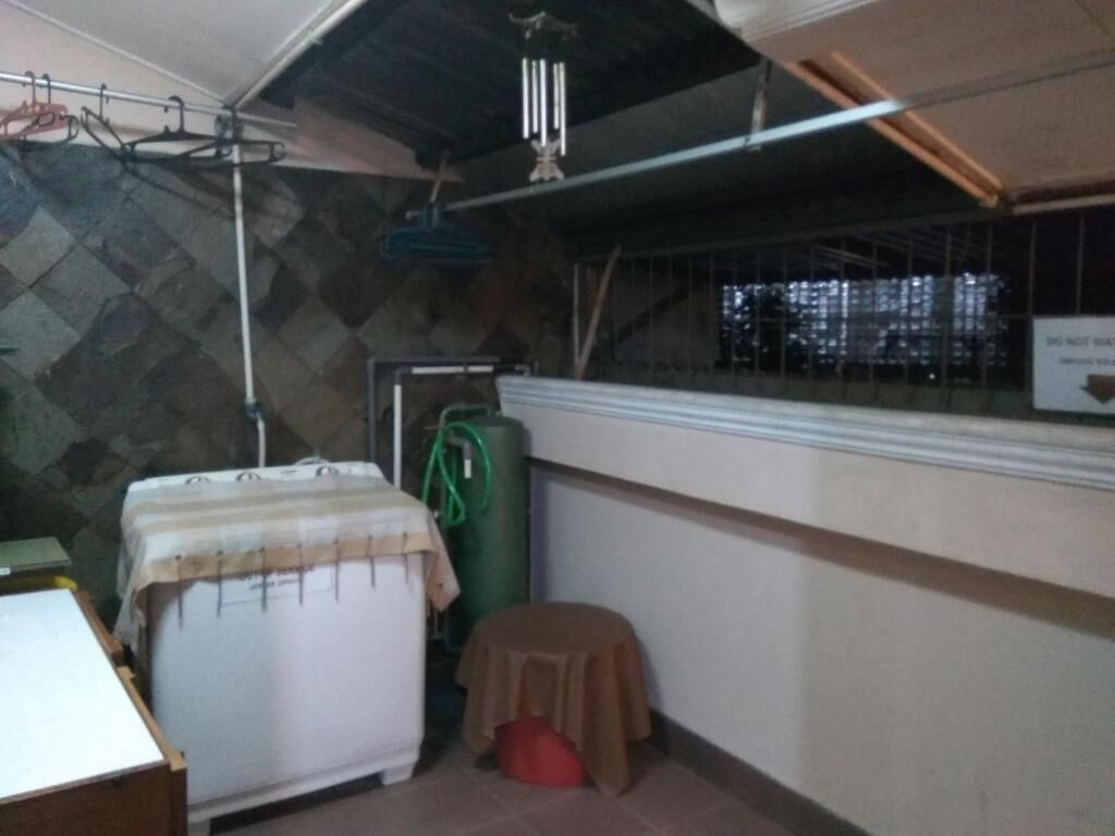 Una habitación pequeña con cama, una mesa, un taburete y una ventana con vistas a edificios.