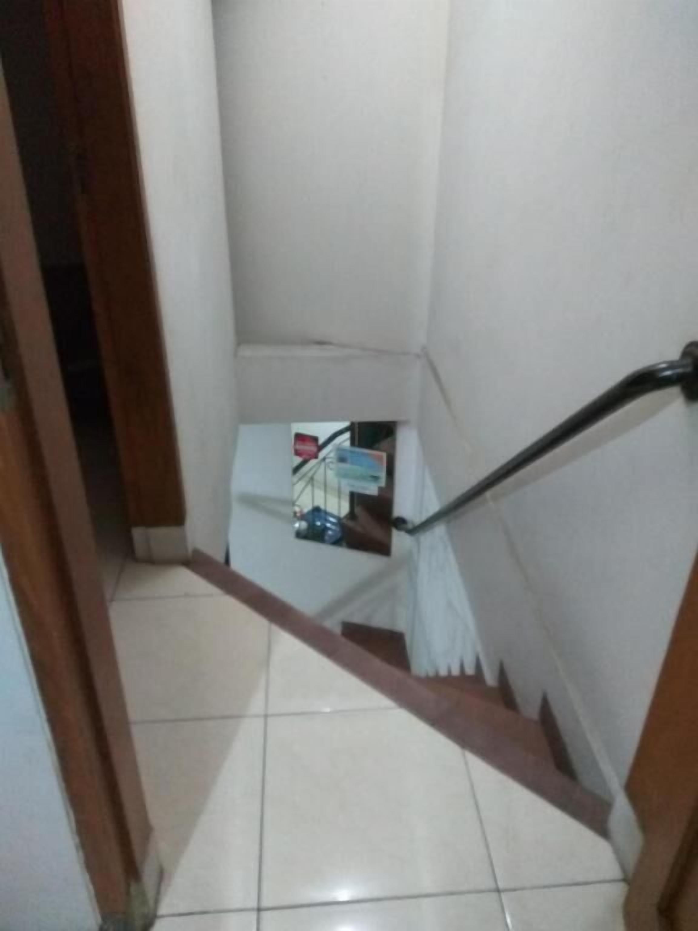 A narrow staircase with a handrail, leading to a landing with a small table and a chair.