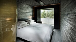 A modern bedroom with a large bed, a view of the outdoors, and a wooden wall.