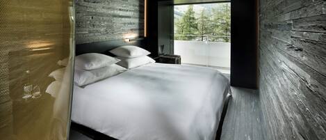 A modern bedroom with a large bed, a view of the outdoors, and a wooden wall.