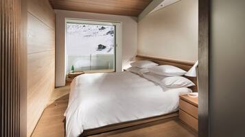Un dormitorio con una cama de madera, una mesita de noche y una ventana con vistas a un paisaje nevado.