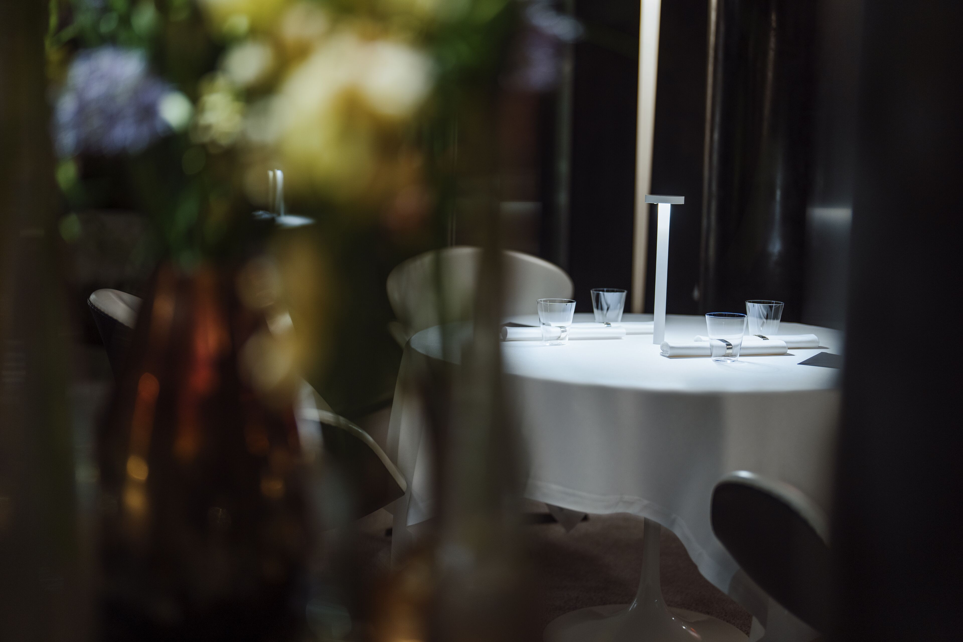 Una mesa redonda de comedor con mantel blanco, rodeada de sillas.