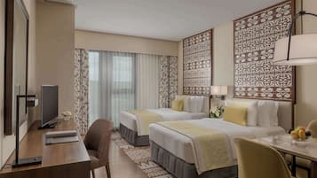 A hotel room with two beds, a desk, a chair, a TV, and decorative panels.