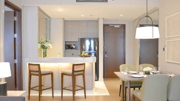 Una cocina moderna con una isla central, taburetes de bar y una zona de comedor con mesa para cuatro.
