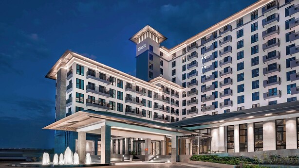 A modern hotel with a prominent tower, a covered entrance, and a spacious outdoor area with a fountain. - Dusit Thani Residence Davao (Davao)