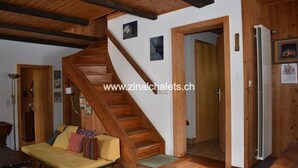 A wooden staircase leading to a second floor, a sofa with cushions, and a refrigerator in a room with wooden walls and floors. - Individual chalet in Zinal - 1 bedroom with 1 bed - 1 bedroom with 3 beds - 2 bedrooms with 2 beds - (Zinal)