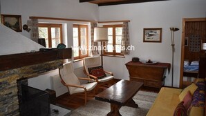 A cozy room with a fireplace, wooden furniture, and a bed with a colorful blanket. - Individual chalet in Zinal - 1 bedroom with 1 bed - 1 bedroom with 3 beds - 2 bedrooms with 2 beds - (Zinal)