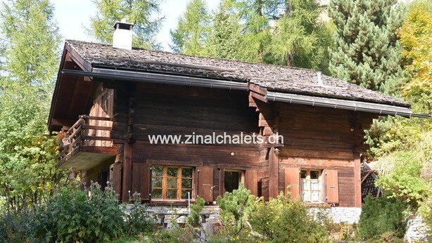 A rustic wooden cabin with a balcony, surrounded by dense forest. - Individual chalet in Zinal - 1 bedroom with 1 bed - 1 bedroom with 3 beds - 2 bedrooms with 2 beds - (Zinal)