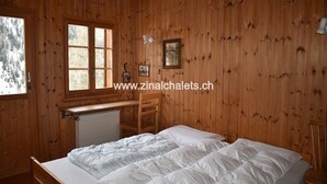 A wooden cabin bedroom with a bed, a desk, and a chair. - Individual chalet in Zinal - 1 bedroom with 1 bed - 1 bedroom with 3 beds - 2 bedrooms with 2 beds - (Zinal)
