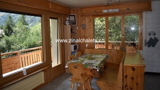 A wooden interior with a dining table, chairs, and a kitchen counter. - Appartment in a building in Zinal - 1 bedroom with 1 double bed (140x200) - 1 bedroom with 2 bunk be (Zinal)
