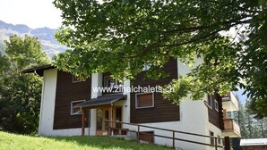 A two-story chalet with a wooden exterior and white walls, a balcony, and a small porch. - Appartment in a building in Zinal - 1 bedroom with 1 double bed (140x200) - 1 bedroom with 2 bunk be (Zinal)