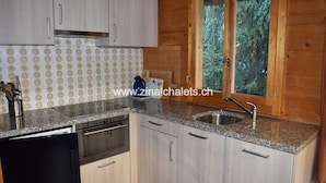 A kitchen with light wood cabinets, a granite countertop, stainless steel appliances, and a window with a view of trees. - Individual chalet in Zinal - 1 bedroom with a double bed (140x200) - 1 bedroom with 2 beds - 1 bedro (Zinal)