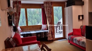 Una sala de estar acogedora con un banco, un sofá rojo y una mesa de comedor.