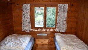 Une cabine avec deux lits, une petite table en bois et une fenêtre avec des rideaux.