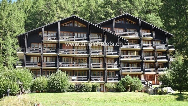 A multi-story chalet with balconies, surrounded by trees. - Appartment in a building in Zinal - 1 bedroom with 2 beds - 1 bedroom with 2 bunk beds - living room (Zinal)