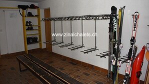 A ski storage room with a bench, a yellow shoe rack, and a wall-mounted ski rack. - Appartment in a building in Zinal - 1 bedroom with 2 beds - 1 bedroom with 2 bunk beds - living room (Zinal)