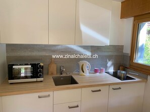 A modern kitchen with a built-in oven, a sink, and a window.