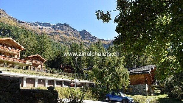 A mountain lodge with a wooden exterior, a balcony, and a view of snow-capped mountains. - Appartment in a chalet in Zinal - 2 bedrooms with 2 beds - living room - TV broadcasting - kitchen - (Zinal)