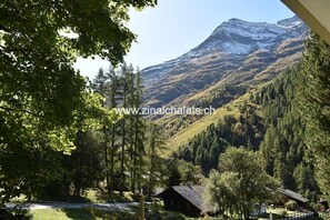 Paisagem montanhosa com uma cabana e uma estrada.