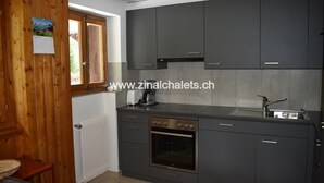 A modern kitchen with grey cabinets, a built-in oven, and a window with a calendar. - Appartment in a chalet in Zinal - 2 bedrooms with 2 beds - living room - TV broadcasting - kitchen - (Zinal)