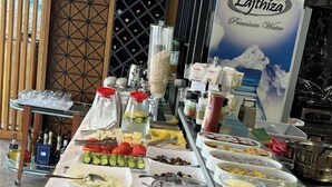 A buffet with various food items including a bundt cake, watermelon slices, and pastries. - Area Hotel (Ksamil)