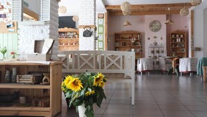 Un interior acogedor con un banco de madera, una pared blanca con un reloj y una repisa de madera con varios objetos.
