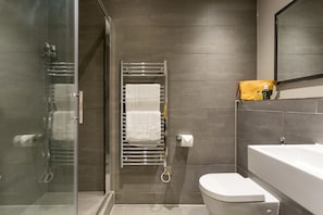 Superior studio suite | Badkamer | Een douche, designer toiletartikelen, een haardroger, handdoeken