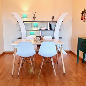 A dining area with a white table, two white chairs, and a green cabinet. - Charming Apartment Surrounded by Nature Cerquita del Rio Ebro (Deltebre)
