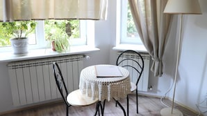 Une pièce chaleureuse avec une petite table ronde, une plante en pot et un radiateur.