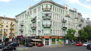 Un immeuble à plusieurs étages, doté d’une façade verdoyante, d’une enseigne « ROSHEN » bien visible et de balcons.