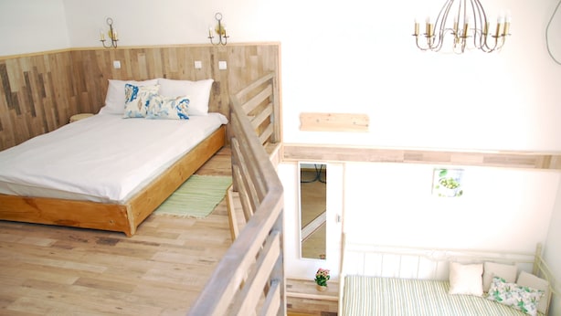 Une chambre à coucher avec un lit en bois, un plus petit lit, un lustre et une petite table sur laquelle est posée une plante.