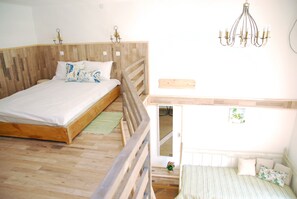 Un dormitorio con una cama de madera, una cama más pequeña, una araña y una mesita con una planta.