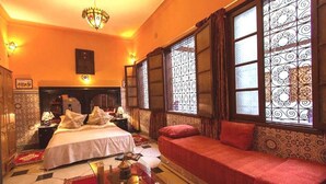 Una habitación con una cama, un sofá, una mesita de noche y una mesa con lámpara.